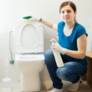 woman in bathroom with sponge and cleaner at  home